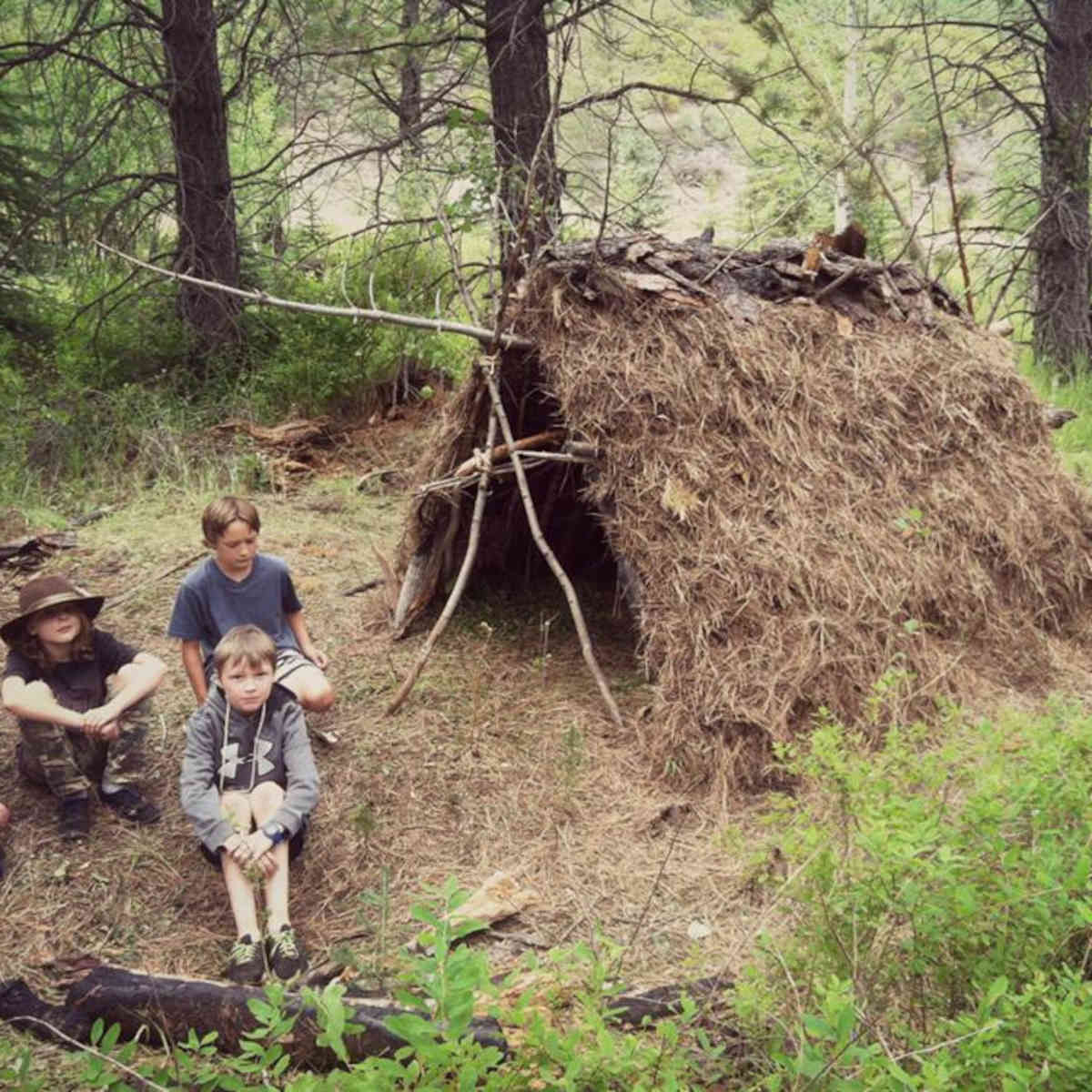 This is a photograph of kids sitting by the fort they built.